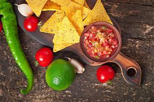 Mexicaanse nacho chips en salsa duik in kom op houten achtergrond foto