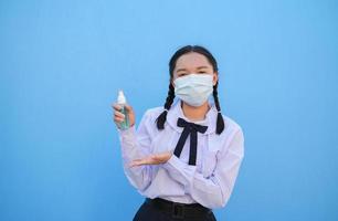 schoolmeisje draag masker op blauwe achtergrond, terug naar school. foto