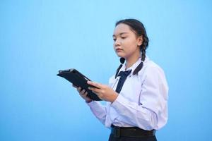 schoolmeisje met tablet op blauwe achtergrond. foto