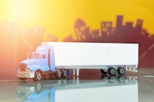 blauw containervrachtwagenspeelgoed met mock-up containertrailer zijaanzicht, selectieve aandacht, op de achtergrond van de wazige stad foto