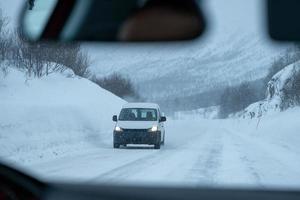 busje rijden op snelweg weg met sneeuw bedekt met sneeuwstorm foto