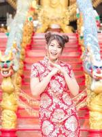 een mooi Aziatisch meisje in een Chinees nationaal kostuum steekt zijn handen op om te buigen foto