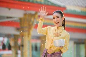 mooie thaise meisjes in thaise kostuums houden waterkommen vast en sprenkelen water met hun handen op songkran festival foto