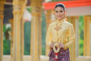 Aantrekkelijke thaise vrouw in een oude thaise jurk houdt een verse bloemenslinger vast als eerbetoon aan Boeddha om een wens te doen op het traditionele songkran-festival in thailand foto