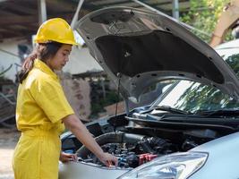 de vrouw in het monteuruniform opent de radiateurdop van de motor om het waterpeil te controleren foto