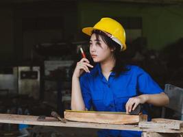 vrouw die in mechanisch uniform werkt en meetinstrumenten gebruikt om houten platen in de fabriek te snijden foto