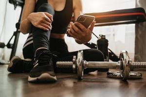 verlies van vrouw met behulp van slimme telefoon tijdens het trainen in de fitnessruimte. sport- en technologieconcept. levensstijlen en gezondheidszorg thema. foto