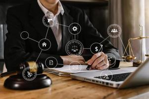 rechtvaardigheid en recht concept.male rechter in een rechtszaal de hamer, werken met slimme telefoon en laptop en digitale tabletcomputer op houten tafel in ochtendlicht foto