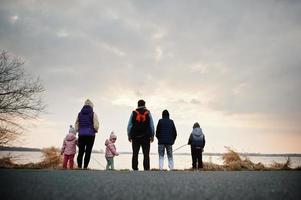 achterkant van gezin met vier kinderen aan de oever van het meer. foto