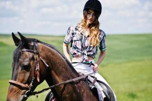 jong mooi meisje rijdt op een paard op een veld op een zonnige dag. foto