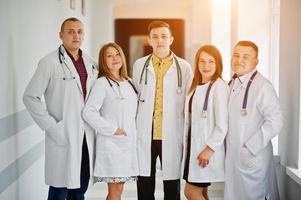 groep jonge artsen in witte jassen poseren in het ziekenhuis. foto