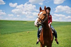 jong mooi meisje rijdt op een paard op een veld op een zonnige dag. foto