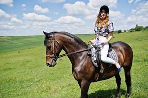 jong mooi meisje rijdt op een paard op een veld op een zonnige dag. foto