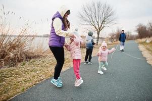 moeder met kinderen springen en hebben plezier op het pad bij het meer. foto