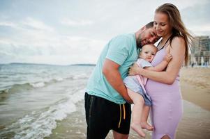 zomervakanties. ouders en mensen buitenactiviteiten met kinderen. fijne familievakanties. vader, zwangere moeder, dochtertje op zee zandstrand. foto