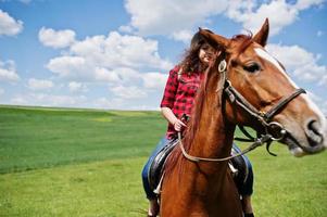 jong mooi meisje rijdt op een paard op een veld op een zonnige dag. foto