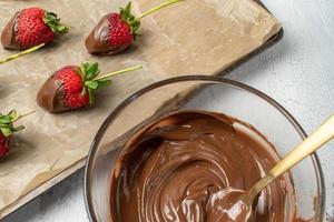 dienblad met aardbeien met stengels gedoopt in chocolade plat gelegd foto