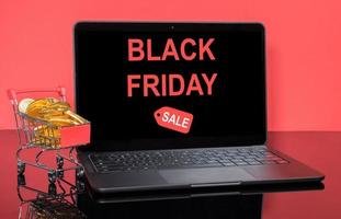 moderne laptopcomputer met black friday-verkoopscherm met winkelwagen en gouden munten foto