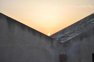 zonsondergang achter huizen foto