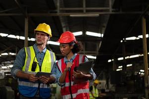 de buitenlandse hoofdingenieur kwam de oude mechanische fabriek inspecteren. er is een Afrikaanse vrouwelijke monteur die details en voortgangsrapporten uitlegt foto