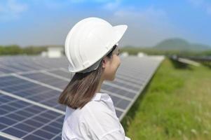 vrouwelijke ingenieur met helm in fotovoltaïsche celboerderij of zonnepanelenveld, milieuvriendelijke en schone energie. foto