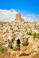 verticale achteraanzicht blanke jonge vrouwelijke toerist in jurk met smartphone capture ortachisar kasteel op vakantie foto