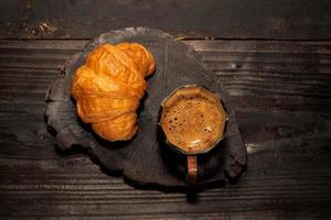 ontbijt eten croissant in bord en koffie op houten tafel. foto