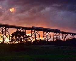 trein gaat over een brug bij zonsondergang foto