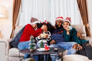 Afro-Amerikaanse familie in kerstthema. gelukkige familie heeft plezier om thuis samen op de bank te zitten. foto