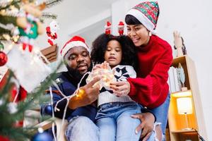 Afro-Amerikaanse familie helpt de kerstboom thuis te versieren. Vrolijk Kerstfeest. foto