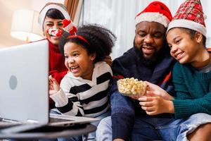 Afro-Amerikaanse familie veel plezier tijdens videogesprek op laptop en samen op de bank zitten foto