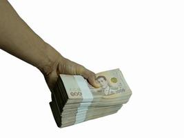 iemands hand met een bankbiljet van 1000 baht op elkaar gestapeld totaal bedrag 1000000 baht op een witte achtergrond. foto