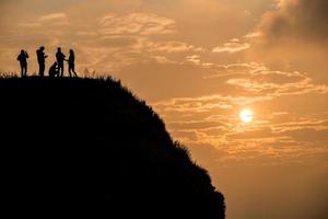 vrienden staan op de top van de berg met prachtige zonsopgang. in phu chi fah nationaal park van de provincie chiang rai in thailand. foto