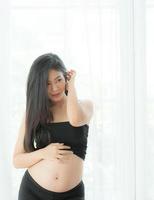 een mooie zwangere vrouw staat op om haar buik op te vangen foto