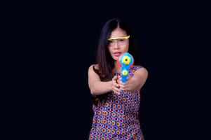 een mooie Aziatische vrouw toont een gebaar terwijl ze een plastic waterpistool vasthoudt tijdens het songkran-festival foto