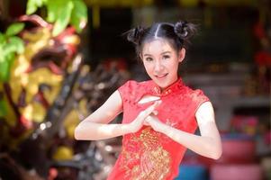 een mooie Aziatische vrouw neemt een foto in een Chinees kostuum, met een traditionele groet voor het Chinese Nieuwjaar