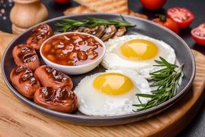 volledig Engels ontbijt met bonen, gebakken eieren, geroosterde worstjes, tomaten en champignons foto