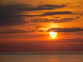 mooie opname van een feloranje zonsonderganghemel boven een zee
