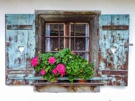 close-up shot van een oud houten raam met bloemen op de dorpel foto
