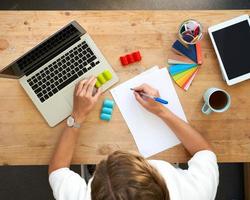 ontwerper werkplek, bovenaanzicht. thuiskantoor - bureau met laptop, handen met kleurrijke set foto