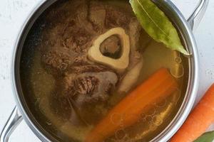 runderbouillon, ossobuco op bot, rijke soep in pan, lang langzaam smachtend koken. foto