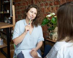 vrouwelijke psycholoog die de hand van de vrouw vasthoudt, coach schrijft naar notitieboekje. sessie van revalidatietherapie foto