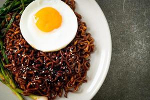 gedroogde Koreaanse pittige zwarte saus instant noedels met gebakken ei en kimchi foto