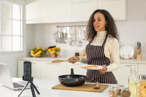 Latijnse vrouw die video opneemt en kookt in de keuken foto