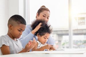 kinderen en grootmoeder tekenen thuis foto's, moeder dochter en zoon spelen vrolijk in de woonkamer foto