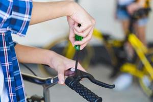 jongen die haar fiets repareert in de garage, kleine jongen die een schroevendraaier gebruikt om de fiets te bevestigen, hobby- en reparatieconcepten foto