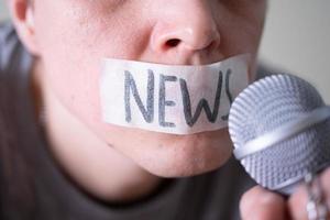 een man propt zijn mond met ducttape en zegt nieuws terwijl hij in een microfoon probeert te praten. foto