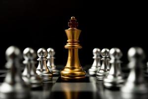 gouden schaakkoning staat om in de buurt te zijn van ander schaken, het concept van een leider moet moed en uitdaging hebben in de competitie, leiderschap en zakelijke visie voor een overwinning in zakelijke games foto