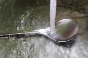 stromend water uit een waterkraan in de afvoer van een chromen gootsteen. foto
