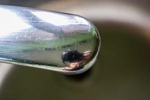 stromend water uit een waterkraan in de afvoer van een chromen gootsteen. foto